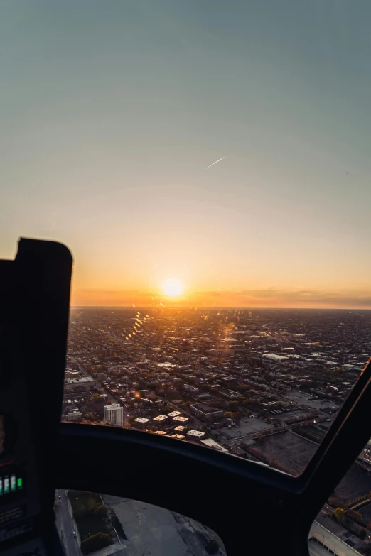 a view of a sunset from the cockpit of a plane, by Brad Holland, pexels contest winner, happening, helicopter footage over city, winter sun, low horizon, wide high angle view