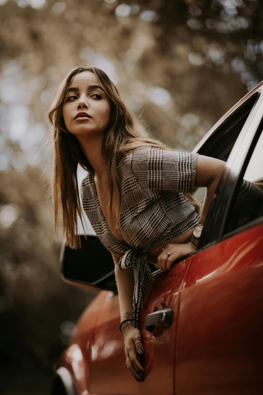 a woman leaning out the window of a red car, an album cover, pexels contest winner, photorealism, isabela moner, wearing plaid shirt, at a fashion shoot, alessio albi