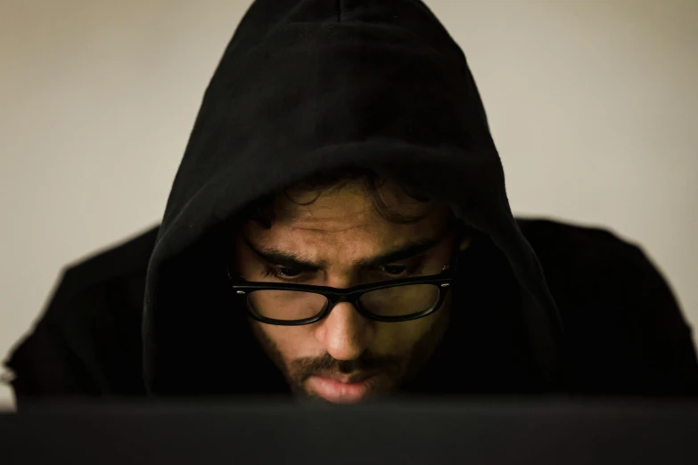 a man in a hoodie looking at a laptop, by Eglon van der Neer, pexels, serial art, wearing black glasses, frightened look, brown, black