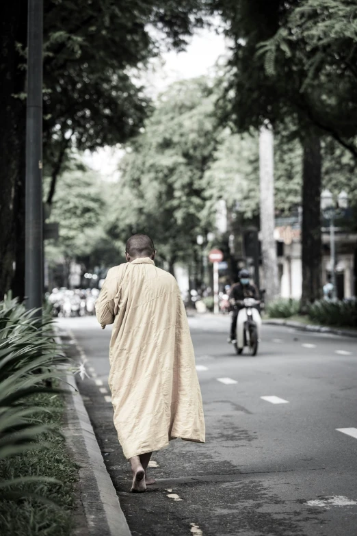a man in a robe is walking down the street, inspired by Cui Bai, happening, vietnam, 2019 trending photo, dirty linen robes, facing away from camera
