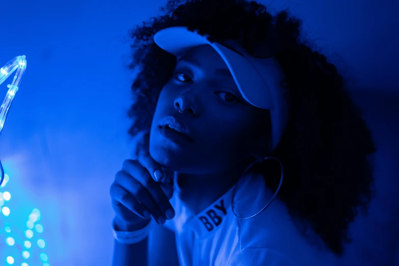 a close up of a person holding a tennis racket, afrofuturism, dramatic white and blue lighting, woman in streetwear, shot with sony alpha 1 camera, black teenage girl