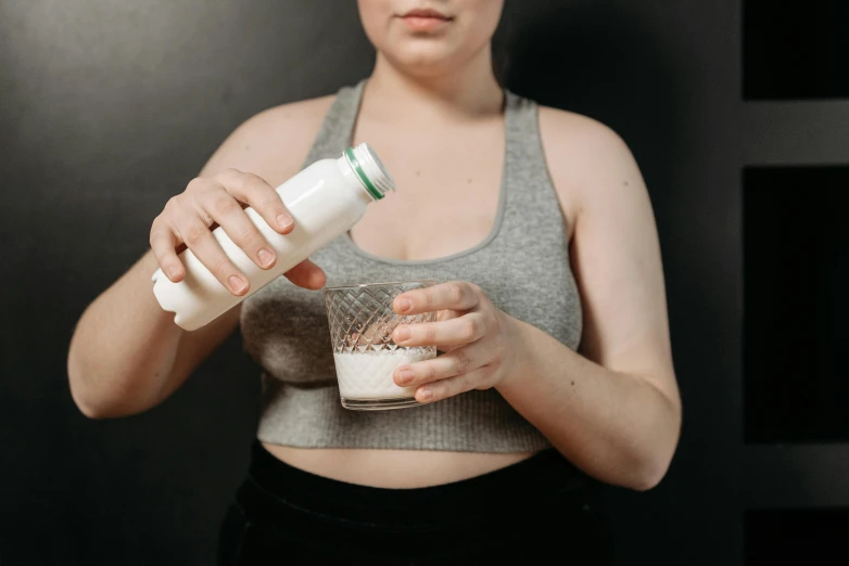 a woman in a tank top is pouring something into a glass, trending on pexels, renaissance, milk, body format, thumbnail, bottle