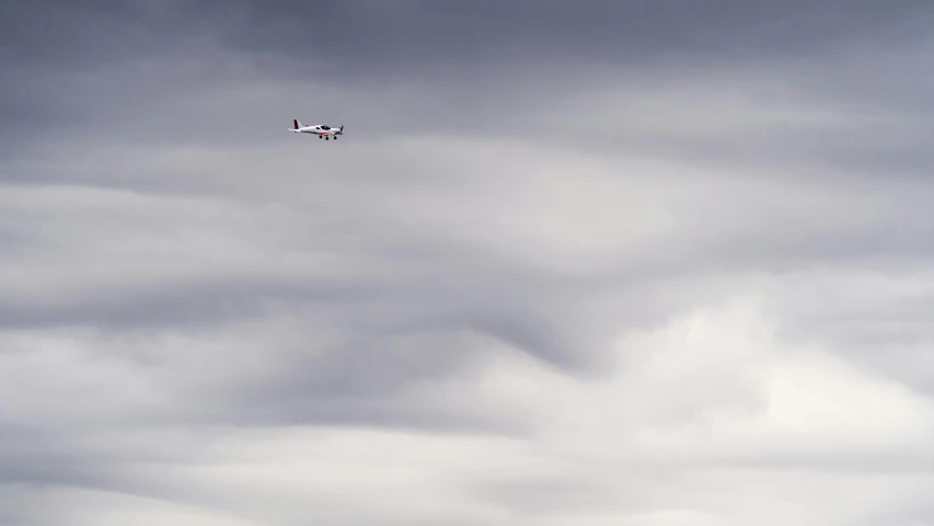 a small plane flying through a cloudy sky, by Neil Blevins, unsplash, cinematic shot ar 9:16 -n 6 -g, low quality photo, white, spitfire