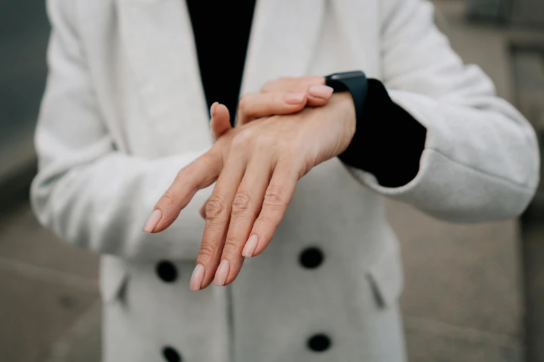 a close up of a person wearing a white coat, by Matija Jama, pexels, painted nails, wearing a watch, wearing a turtleneck and jacket, physically accurate