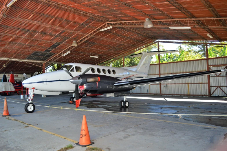 a small propeller plane parked inside of a hangar, hurufiyya, lush surroundings, profile image