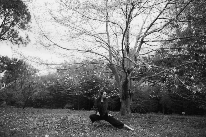 a man sitting on the ground in front of a tree, a black and white photo, arabesque, she is floating in the air, in fall, seseon yoon, lunging at camera :4