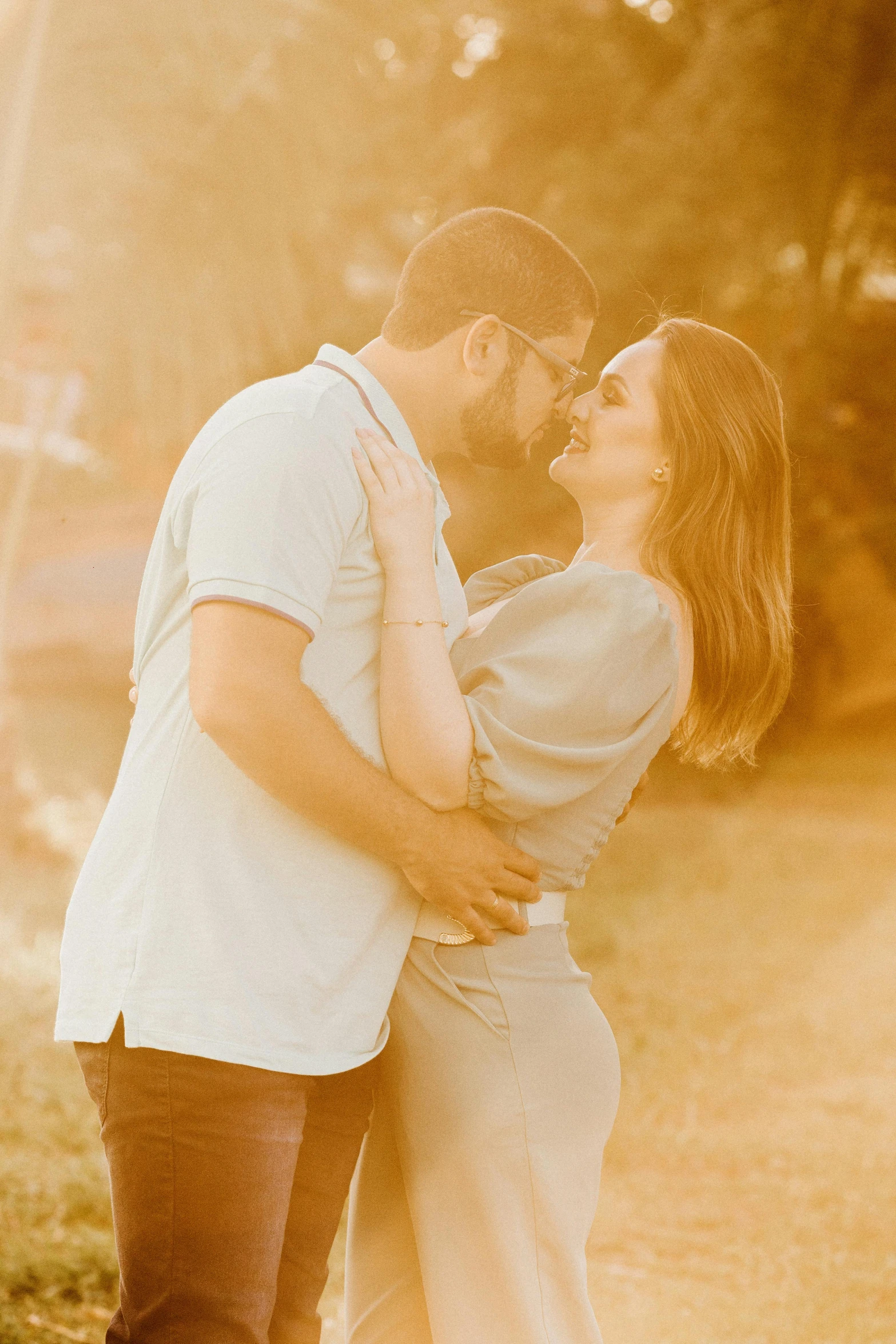 a man and a woman standing next to each other, a colorized photo, pexels contest winner, warm glow, hugging her knees, playful vibe, sunfaded
