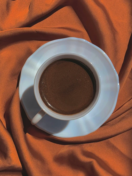a cup of coffee on an orange cloth, by Anna Haifisch, hurufiyya, alessio albi, full frame image, without duplicate image