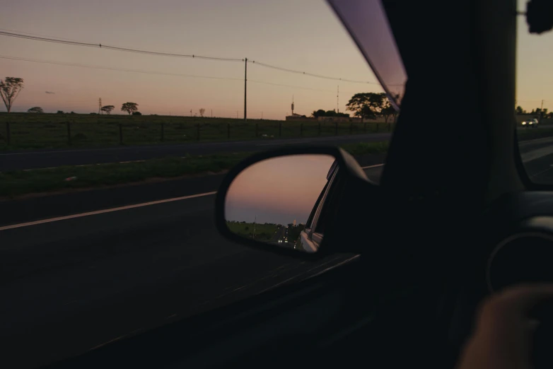 a person's reflection in the side mirror of a car, a picture, unsplash contest winner, dusk light, plain stretching into distance, lachlan bailey, black car