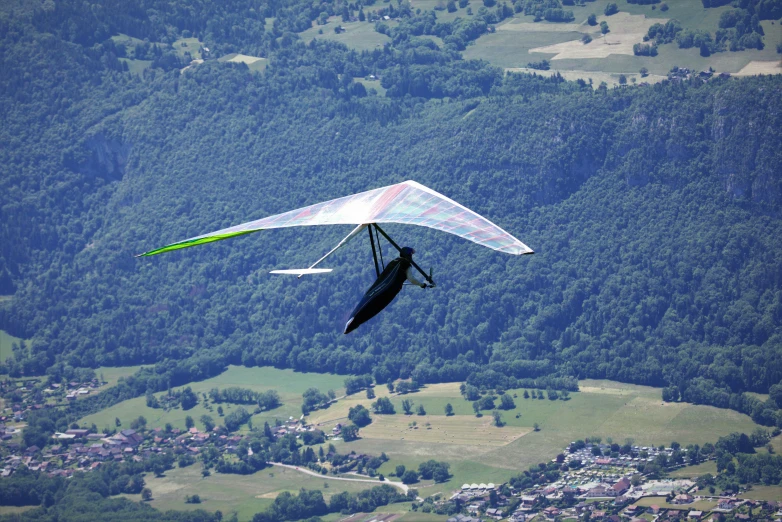 a man flying a hang glider over a lush green hillside, by Jan Rustem, flickr, “ aerial view of a mountain, avatar image, flying vehicles, profile image