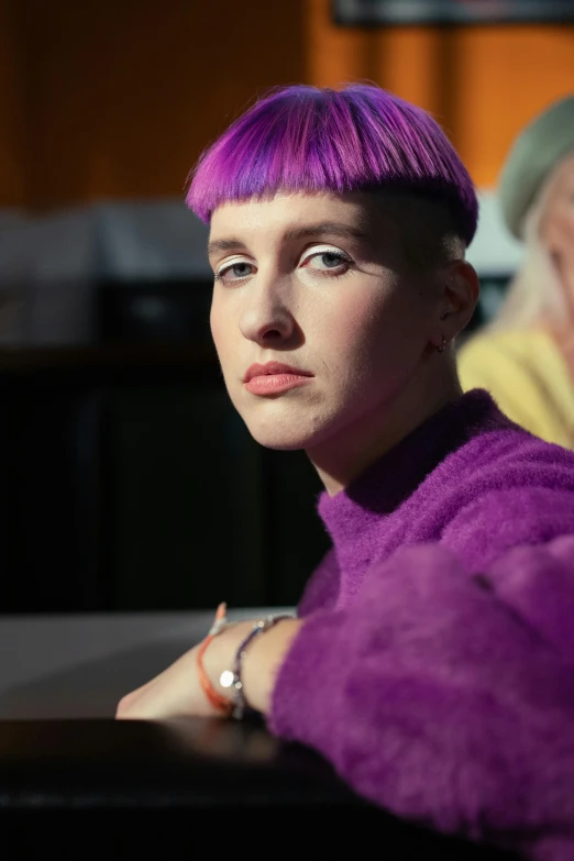 a woman with purple hair sitting at a table, a portrait, trending on pexels, genderless, brutalist fashion show, proud looking away, minna sundberg