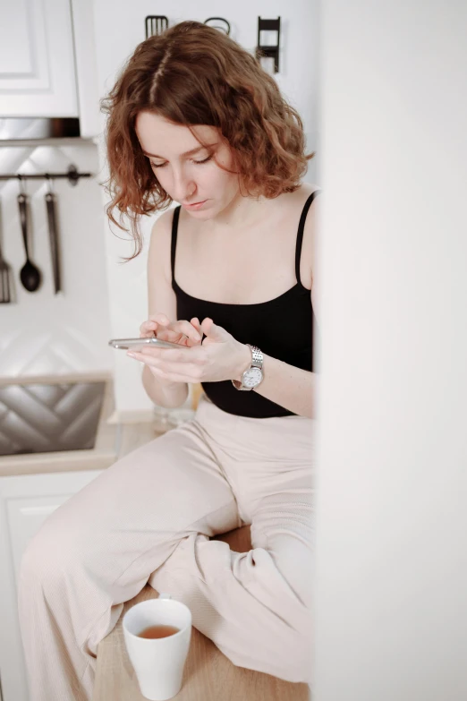 a woman sitting on a kitchen counter looking at her cell phone, trending on pexels, renaissance, wearing tight simple clothes, anna nikonova aka newmilky, avatar image, brown haired