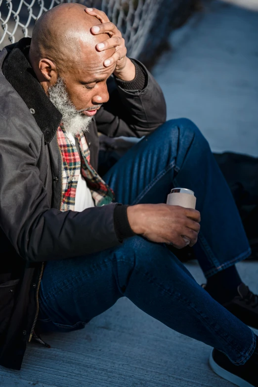 a man sitting on the ground with his head in his hands, trending on pexels, renaissance, grey trimmed beard, african american, zombie holding coffee cup, a man wearing a black jacket