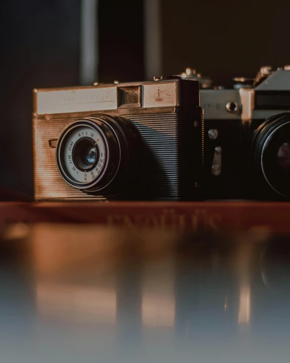 a couple of cameras sitting on top of a wooden table, by Adam Rex, close - up photograph, color photo, high quality image