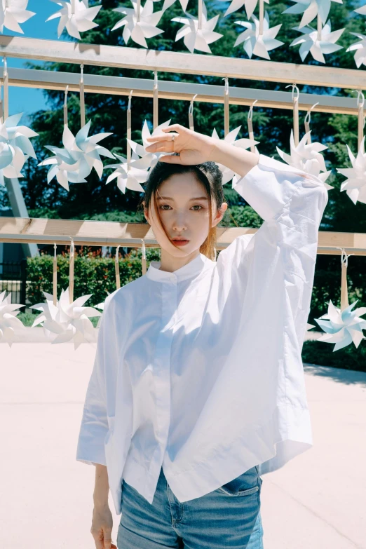 a woman standing in front of a bunch of paper cranes, an album cover, by Torii Kiyomoto, unsplash, wearing white clothes, porcelain pale skin, gemma chan girl portrait, ✨🕌🌙