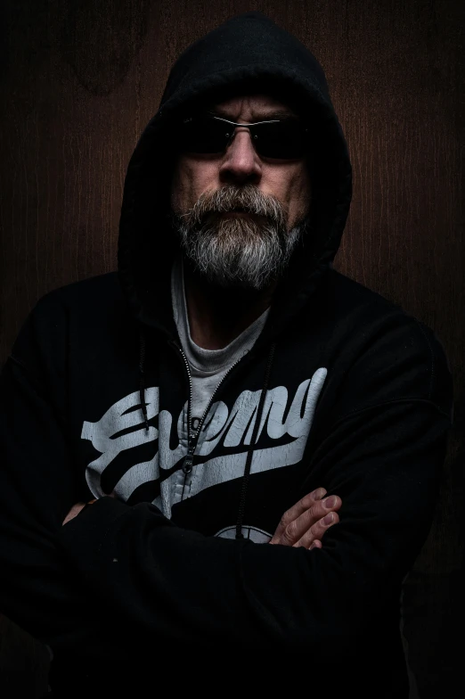 a man with a beard wearing sunglasses and a hoodie, ray swanland, strong lighting, bill stoneham, evil posed