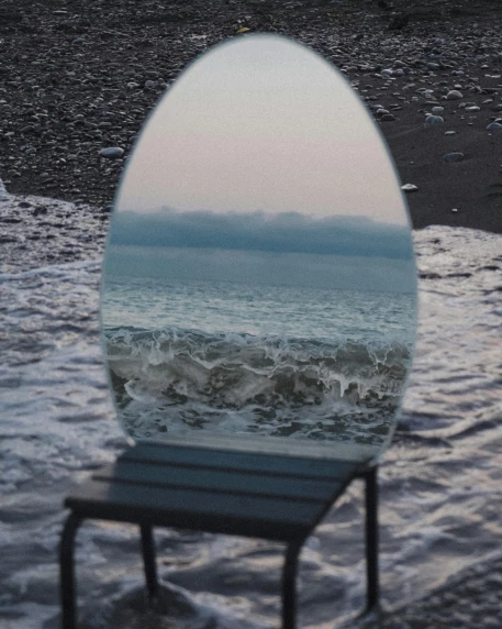 a mirror sitting on top of a beach next to a chair, a picture, pexels contest winner, water bubble, very aesthetic, low quality photo, leaked photo