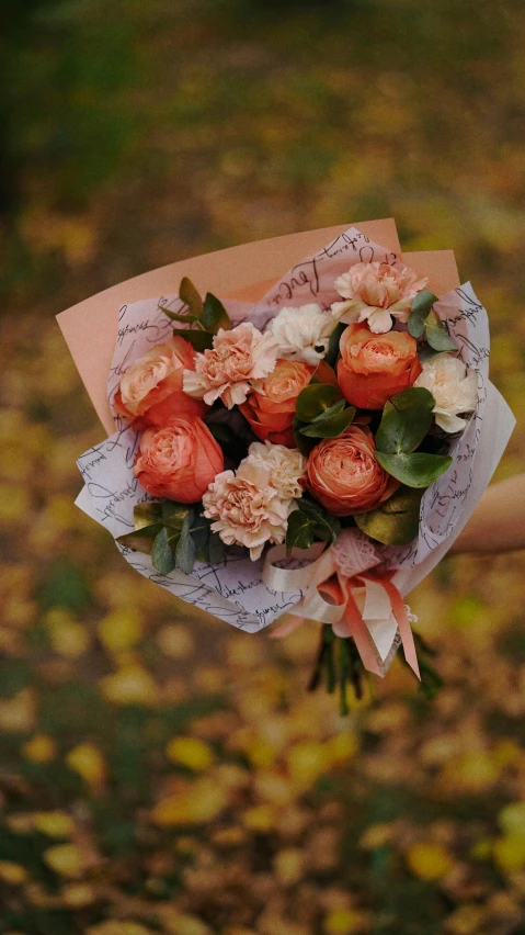 a woman holding a bunch of flowers in her hand, a picture, dark grey and orange colours, thumbnail, low quality photo, autumnal