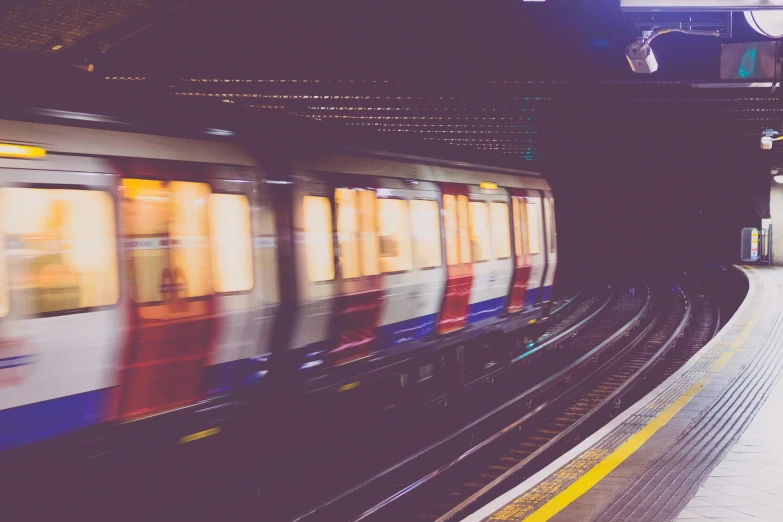 a train traveling through a train station next to a platform, by Carey Morris, unsplash, down in the sewers of london, square, underexposed, trending on