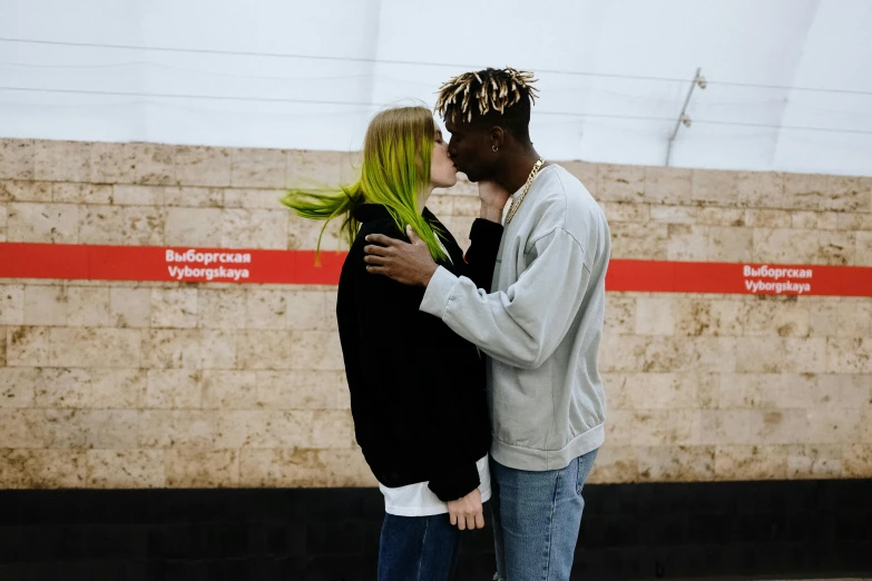 a man and a woman kissing in front of a wall, trending on pexels, bright green hair, in a subway, virgil abloh, hannah yata charlie immer