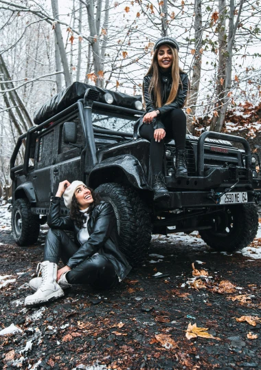 a woman sitting on top of a black jeep, a picture, by Adam Marczyński, pexels contest winner, hurufiyya, alena aenami and lilia alvarado, square, low quality photo, winter