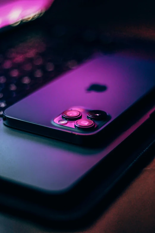 a cell phone sitting on top of a laptop computer, by Niko Henrichon, trending on pexels, holography, black and purple, iphone 12 camera, glowing buttons, color graded