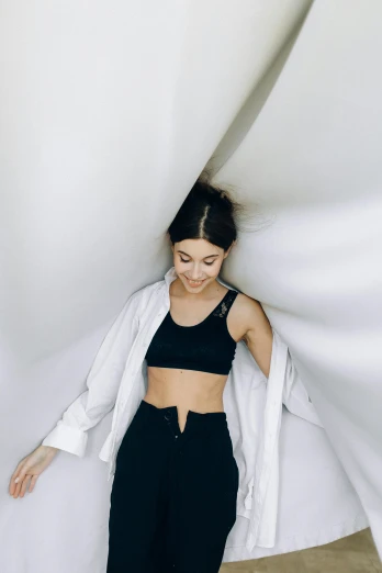 a woman in black pants and a white jacket, trending on pexels, minimalism, wearing leotard, smiling down from above, white room, beautiful midriff