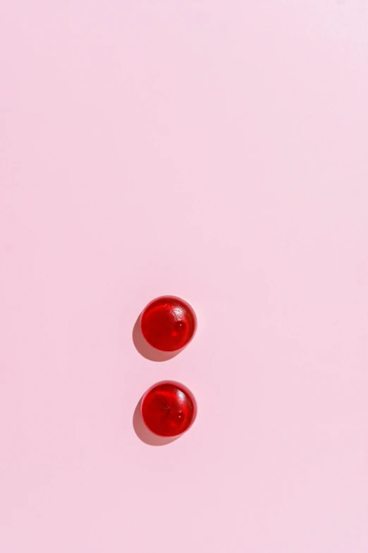 two red pills sitting on top of a pink surface, trending on pexels, translucent orbs, cropped red yoga short, top-down view, looking off to the side