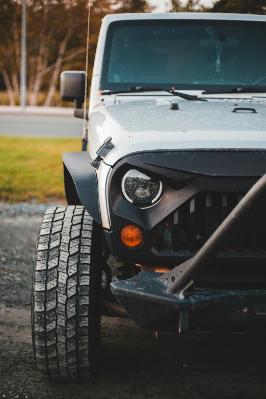 a white jeep parked on the side of a road, by Jason Felix, pexels contest winner, dynamic closeup, square jaw, aftermarket parts, headlights