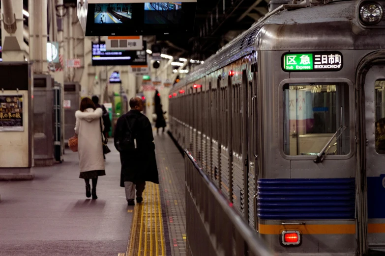 a couple of people that are standing next to a train, flickr, sōsaku hanga, underground facility, facing away from camera, 🚿🗝📝