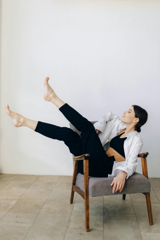 a woman sitting in a chair with her legs up, pexels contest winner, arabesque, wearing pants, andrea savchenko, natural tpose, jen atkin