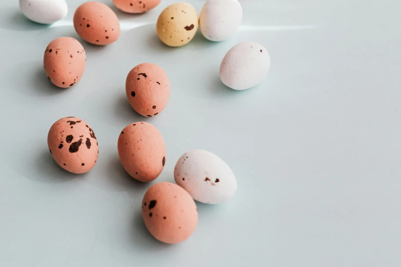 a bunch of eggs sitting on top of a table, by Emma Andijewska, trending on pexels, candy decorations, speckled, beans, pastel pink concrete