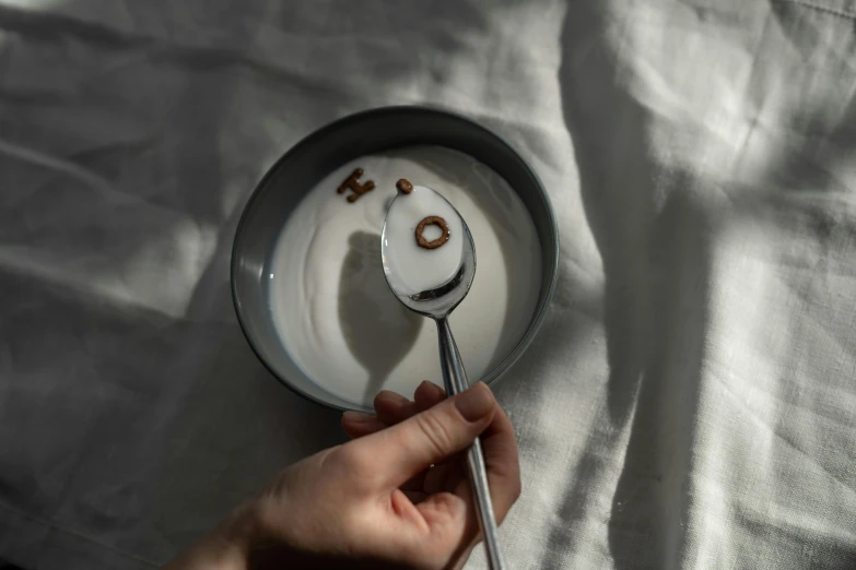 a person holding a spoon over a bowl of cereal, by Emma Andijewska, hidden message, yogurt, silver monocle, oh no