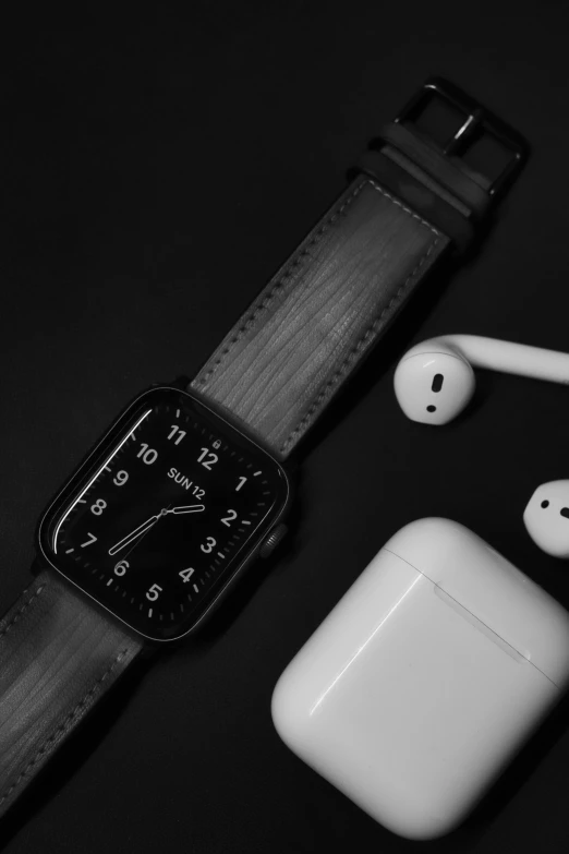 an apple watch sitting next to a pair of airpods, a black and white photo, inspired by Robert Mapplethorpe, trending on pexels, dark aesthetic, monochrome:-2, icon, wooden