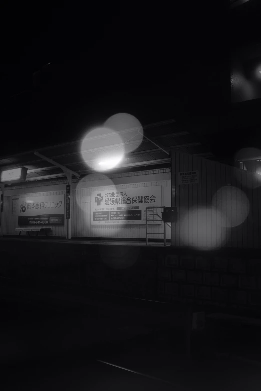 a black and white photo of a train station, a black and white photo, by Awataguchi Takamitsu, glowing orbs, convenience store, nightfall. quiet, police station