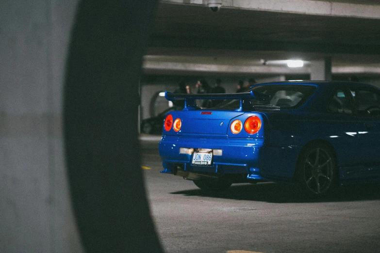 a blue sports car parked in a parking garage, inspired by Kanō Hōgai, pexels contest winner, in a modified nissan skyline r34, rear lighting, profile picture 1024px, car jump