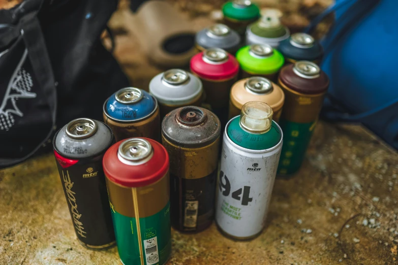 a group of spray cans sitting on top of a rock, an airbrush painting, unsplash, inspect in inventory image, close up portrait shot, sustainable materials, instagram post