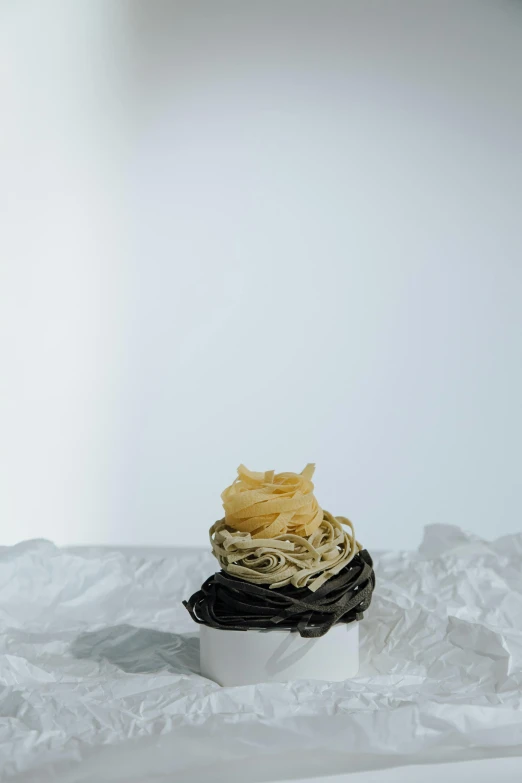 a cupcake sitting on top of a white plate, an abstract sculpture, by Jessie Algie, unsplash, renaissance, served with pasta, several layers of fabric, black on white background, medium format