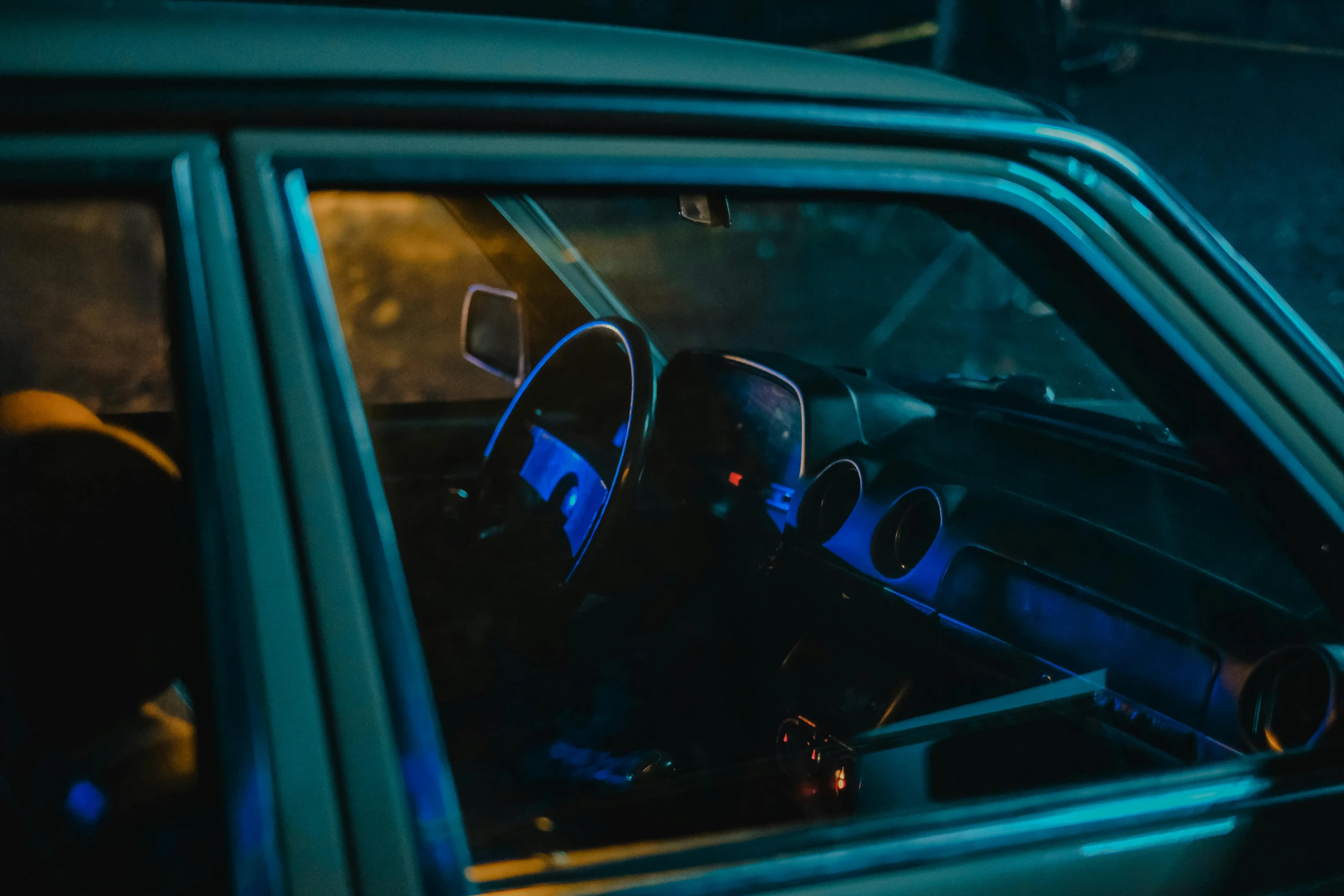 a man sitting in the driver's seat of a car, inspired by Elsa Bleda, blue headlights, instagram post, old car, blue neon