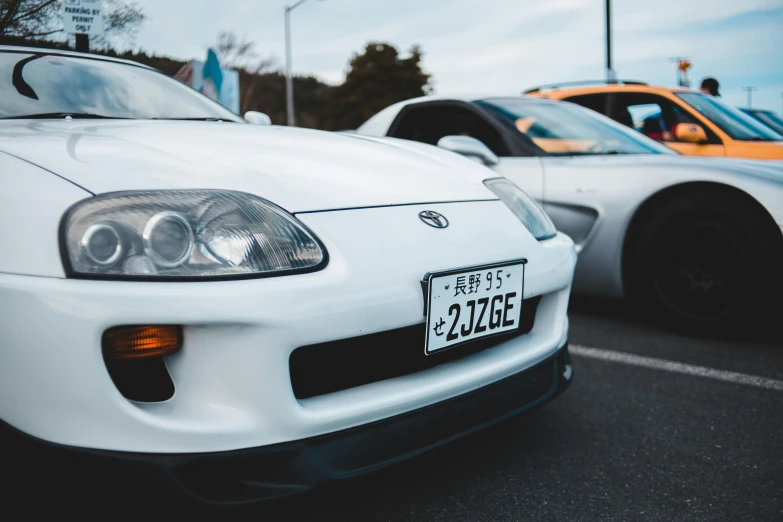 two cars parked next to each other in a parking lot, a picture, unsplash, shin hanga, toyota supra, white mechanical details, 2 0 0 0's photo, 2263539546]