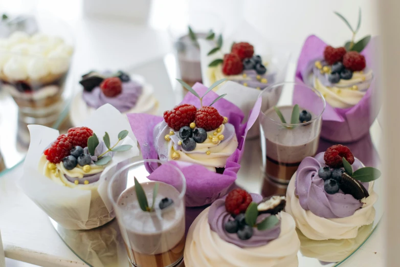 a close up of a plate of cupcakes on a table, by Lee Loughridge, pexels, white and purple, berries, basil gogos, creamy