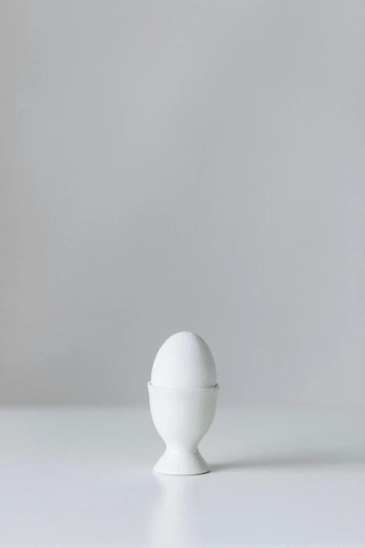 a white egg sitting on top of a white table, inspired by Marina Abramović, postminimalism, posed in profile, pestle, shot on hasselblad, white finish