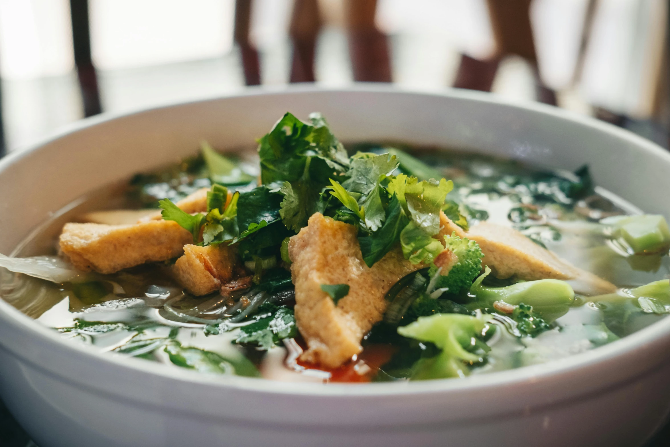 a bowl of soup sitting on top of a table, inspired by Tan Ting-pho, unsplash, lush greens, square, battered, hot food