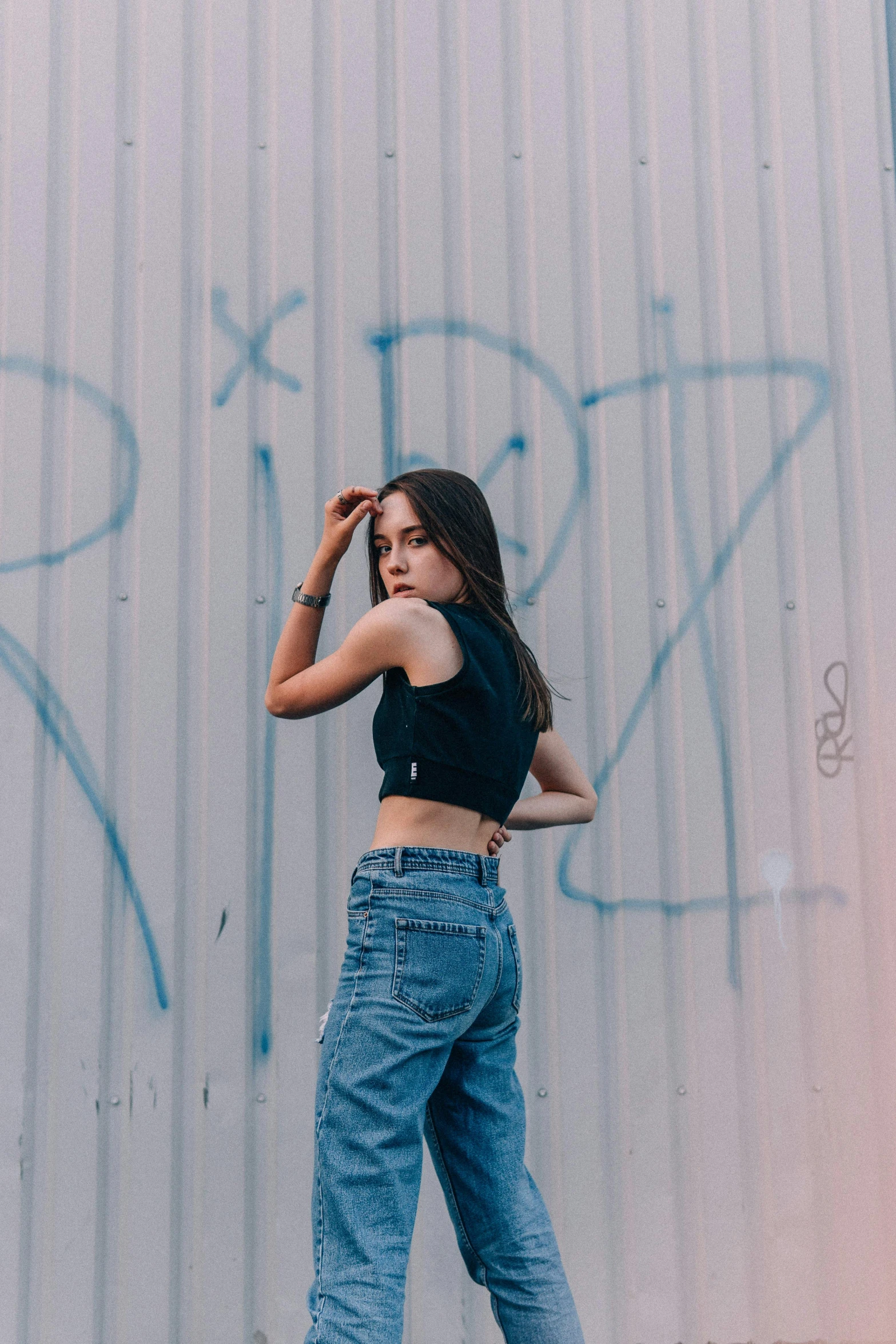 a woman standing in front of a wall with graffiti, inspired by Elsa Bleda, trending on pexels, croptop, chloe bennet, 90s photo, concert