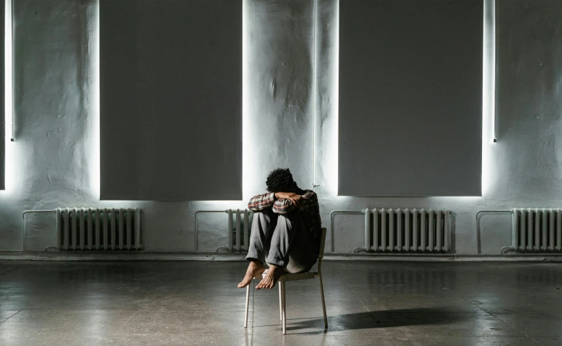 a person sitting on a chair in a room, antipodeans, heartbroken, restrained, sitting down, backfacing