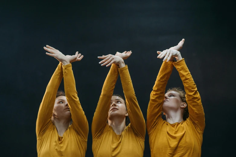 a couple of women standing next to each other, an album cover, by Attila Meszlenyi, unsplash, antipodeans, contemporary dance poses, mustard, trio, with arms up