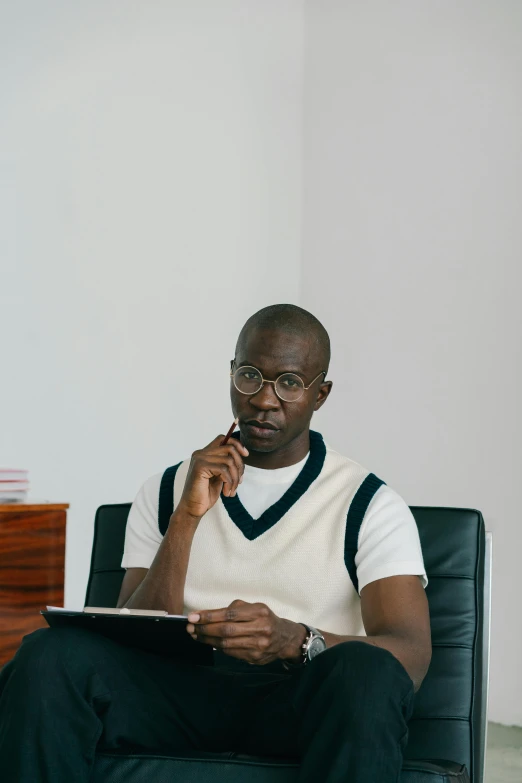 a man sitting in a chair talking on a cell phone, atiba jefferson, holding notebook, 2019 trending photo, looking serious