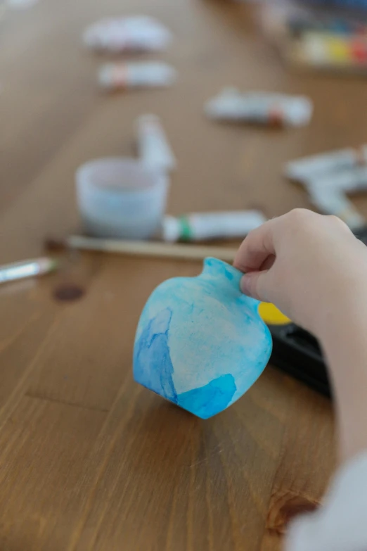 a close up of a child's hand on a table, inspired by Gerard David, unsplash, process art, holding a balloon, tissue ornament, ultrawide watercolor, squirtle