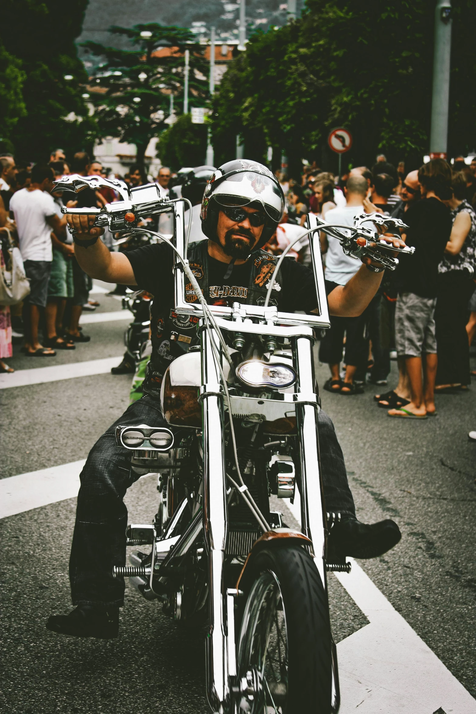 a man riding on the back of a motorcycle down a street, pexels contest winner, in style of chrome hearts, pride parade, barcelona, slightly smiling