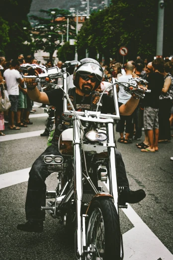 a man riding on the back of a motorcycle down a street, pexels contest winner, in style of chrome hearts, pride parade, barcelona, slightly smiling